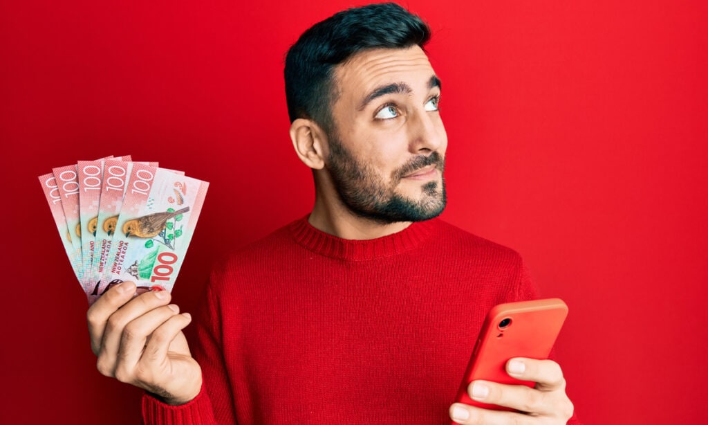 a man holding cash and his phone