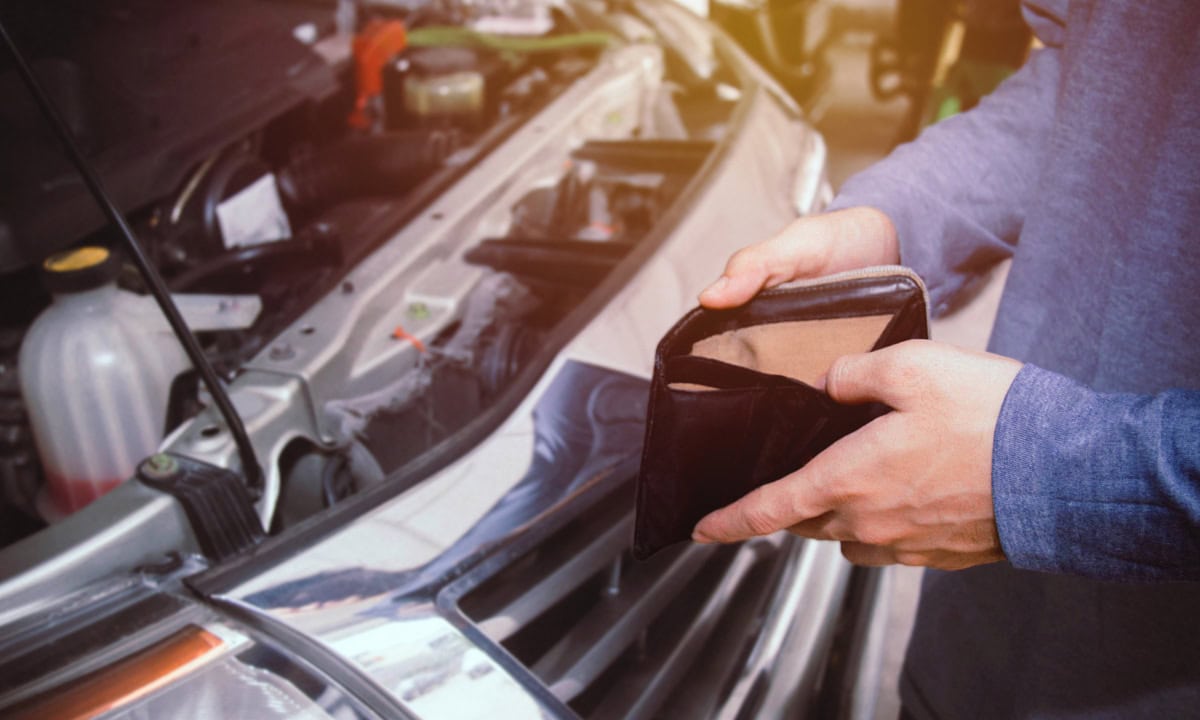 a person standing by their broken down car with an empty wallet